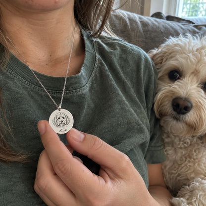 Dog — AI concept: AI concept: an adult in a faded green shirt wearing Alfie’s silver portrait necklace beside the matching cream Maltipoo. Not a customer photograph.