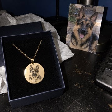 AI concept: A gold REX German shepherd portrait necklace in a gift box beside the dog’s photo on a scratched black desk.