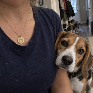 AI concept: Maple the beagle beside a wearer’s navy tee and matching gold custom portrait necklace.